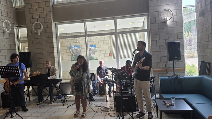 Blind Vision Band, bestehend aus drei Schülern, einer Schülerin und zwei Lehrkräften, steht im Foyer und singt sowie spielt verschiedene Instrumente