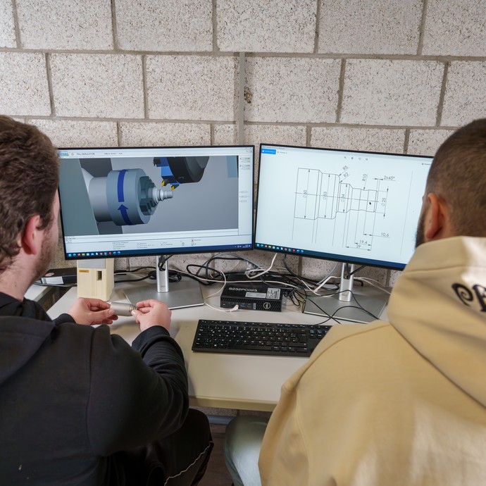 Zwei Schüler schauen sich über CAD und CNC Pläne am PC an. (vergrößerte Bildansicht wird geöffnet)