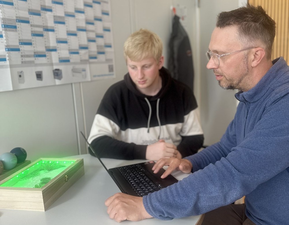 Schulsozialarbeiter und Schüler im Dialog – sitzend an einem Tisch.