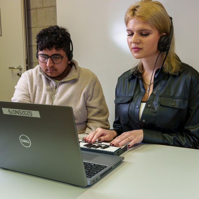 Schüler und Schülerin lesen mit der Braillezeile am Laptop (vergrößerte Bildansicht wird geöffnet)