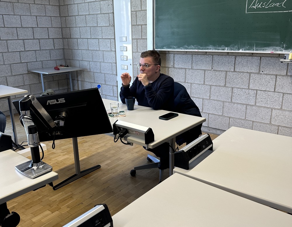 Herr Cramer sitzt vor der Gruppe und trägt seinen Vortrag vor