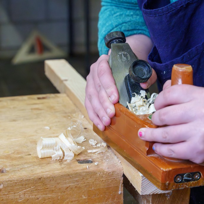 Schülerin arbeitet mit dem Putzhobel an einem Holzstück (vergrößerte Bildansicht wird geöffnet)