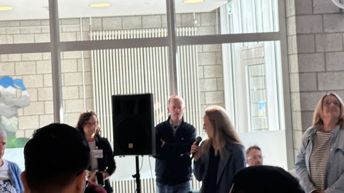 Die Schulleitung, zwei Lehrerinnen sowie Referentinnen und der Schulsozialarbeiter stehen bzw. sitzen vorne im Foyer.