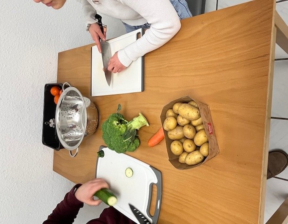 die Bewohner und Bewohnerin des Internats beim Gemüseschneiden