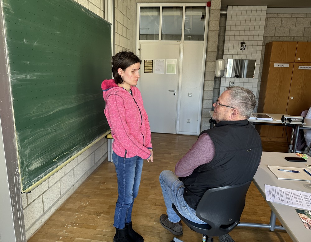 Schülerin steht vor Herr Lehmann und stellt eine Frage