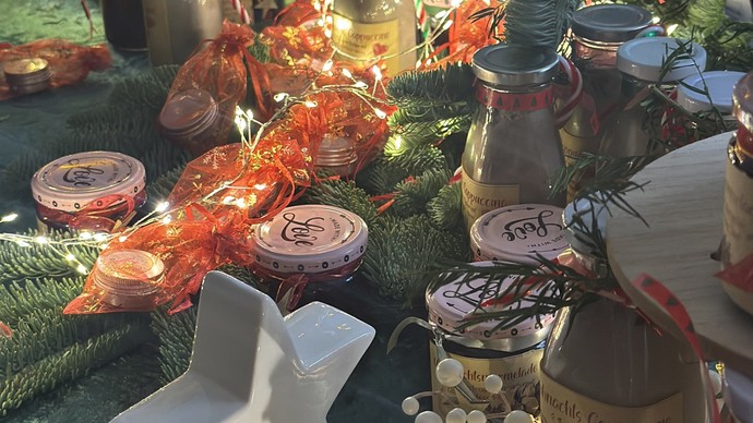 Auf einem weihnachtlich dekorierten Tisch mit Lichterketten, Weihnachtssternen und Tannenzapfen stehen Marmelade und Weihnachtscappuccino.