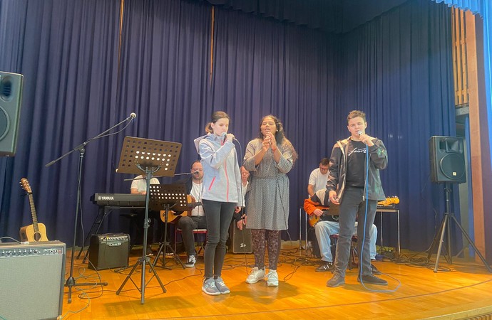 Zwei Schülerin und ein Schüler am Singen