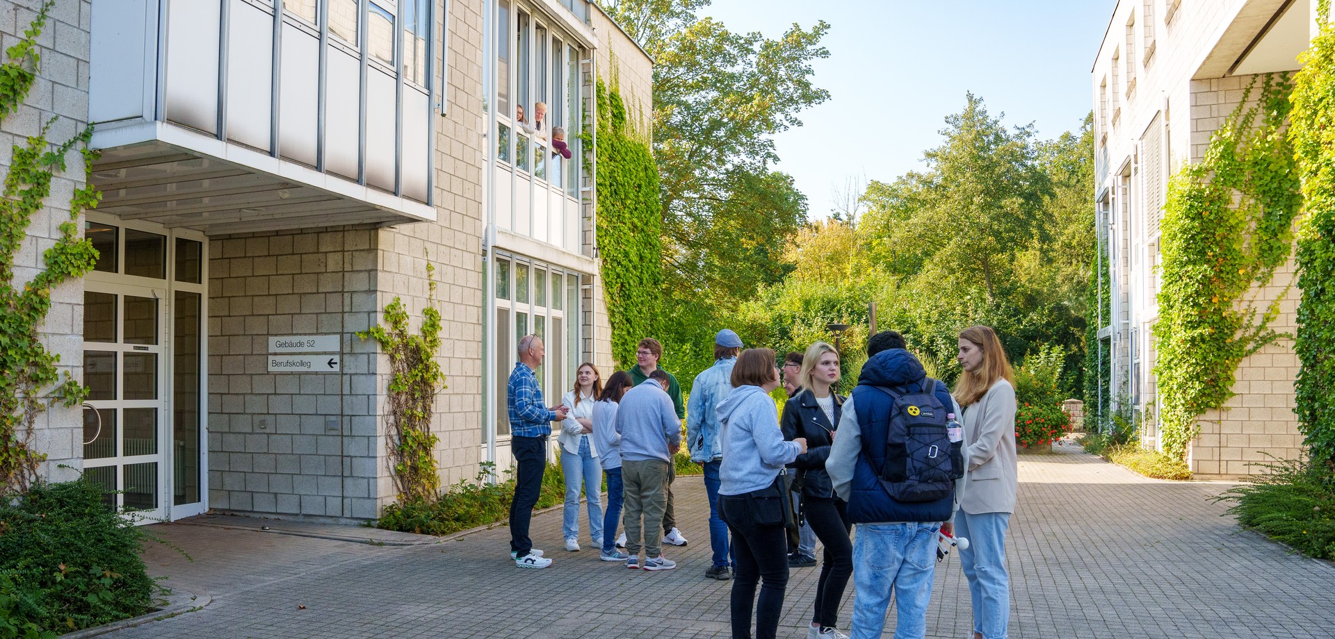 Lehrerinnen und Lehrer sowie Schülerinnen und Schüler stehen auf dem Schulhof.